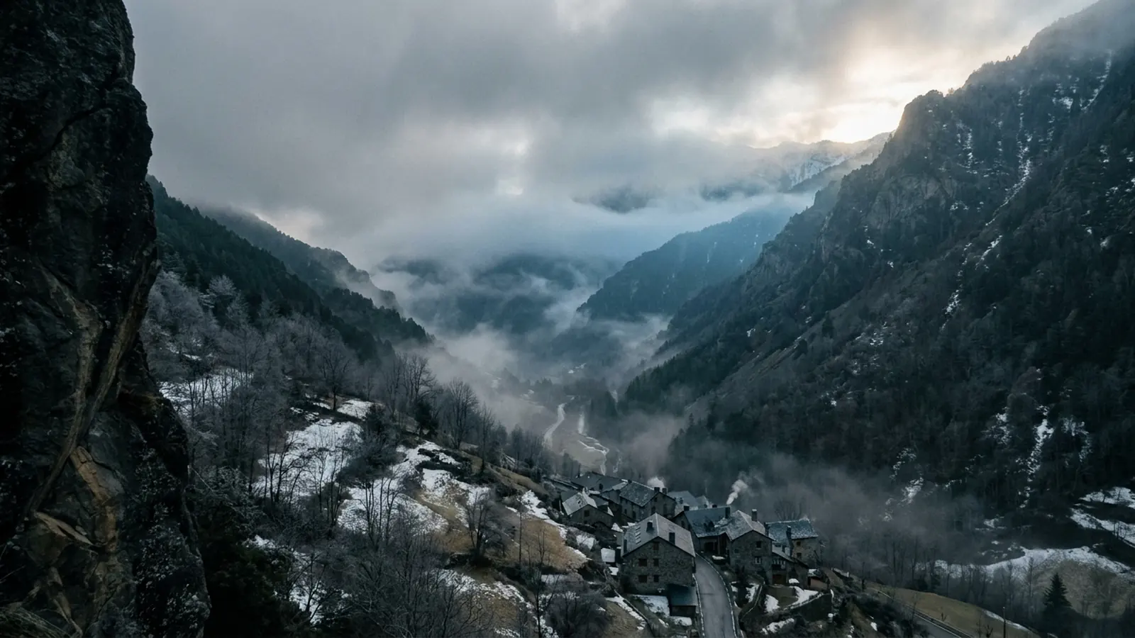 Vall andorrana encaixonada sota núvols baixos a finals d’hivern, poble de pedra al fons