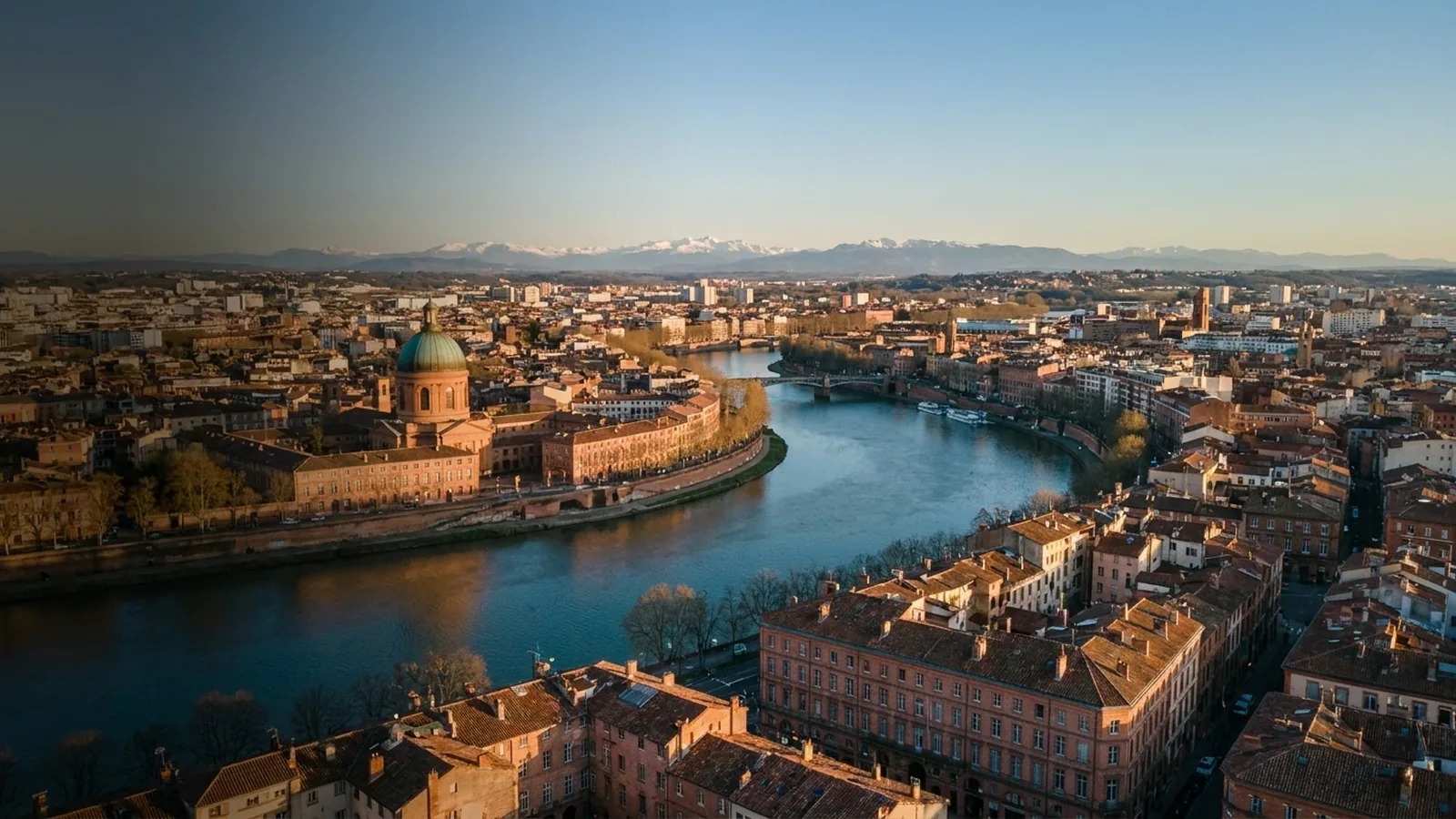 Toulouse, la ville rose, au bord de la Garonne avec les Pyrénées enneigées à l’horizon